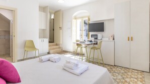 A hotel room with a bed, two chairs, a desk with a computer, a TV, and a staircase leading to another room. - Room 'Lì' with Mountain View, Wi-Fi and Air Conditioning (Scicli)