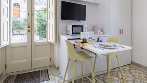 A kitchen with a white countertop, a microwave, a TV, and yellow chairs. - Room 'Lì' with Mountain View, Wi-Fi and Air Conditioning (Scicli)