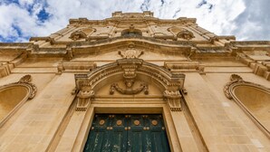 A historic building facade with ornate architectural details, a prominent entrance, and a large green door. - Room 'Lì' with Mountain View, Wi-Fi and Air Conditioning (Scicli)
