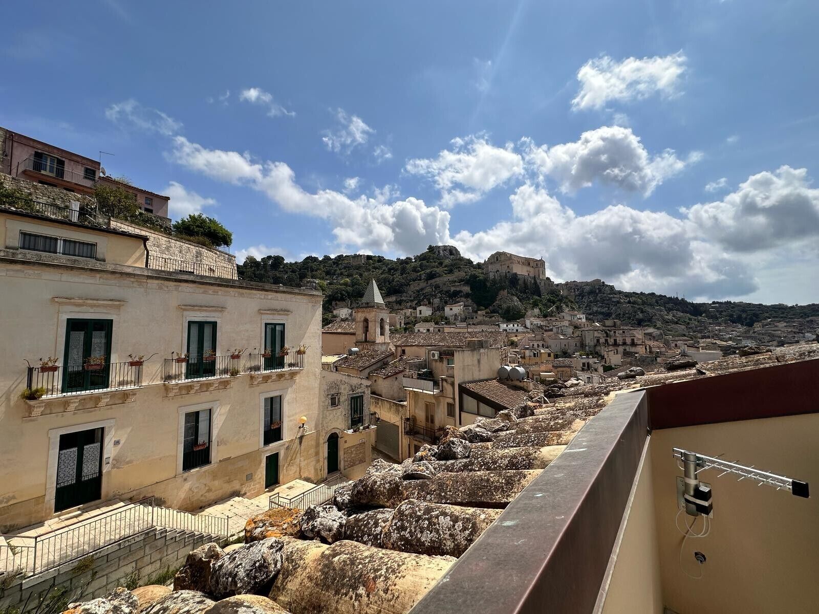A historic town with stone buildings, a prominent church, and a castle on a hill.