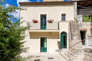 A building with a green door, a balcony with flower boxes, and a stone staircase.