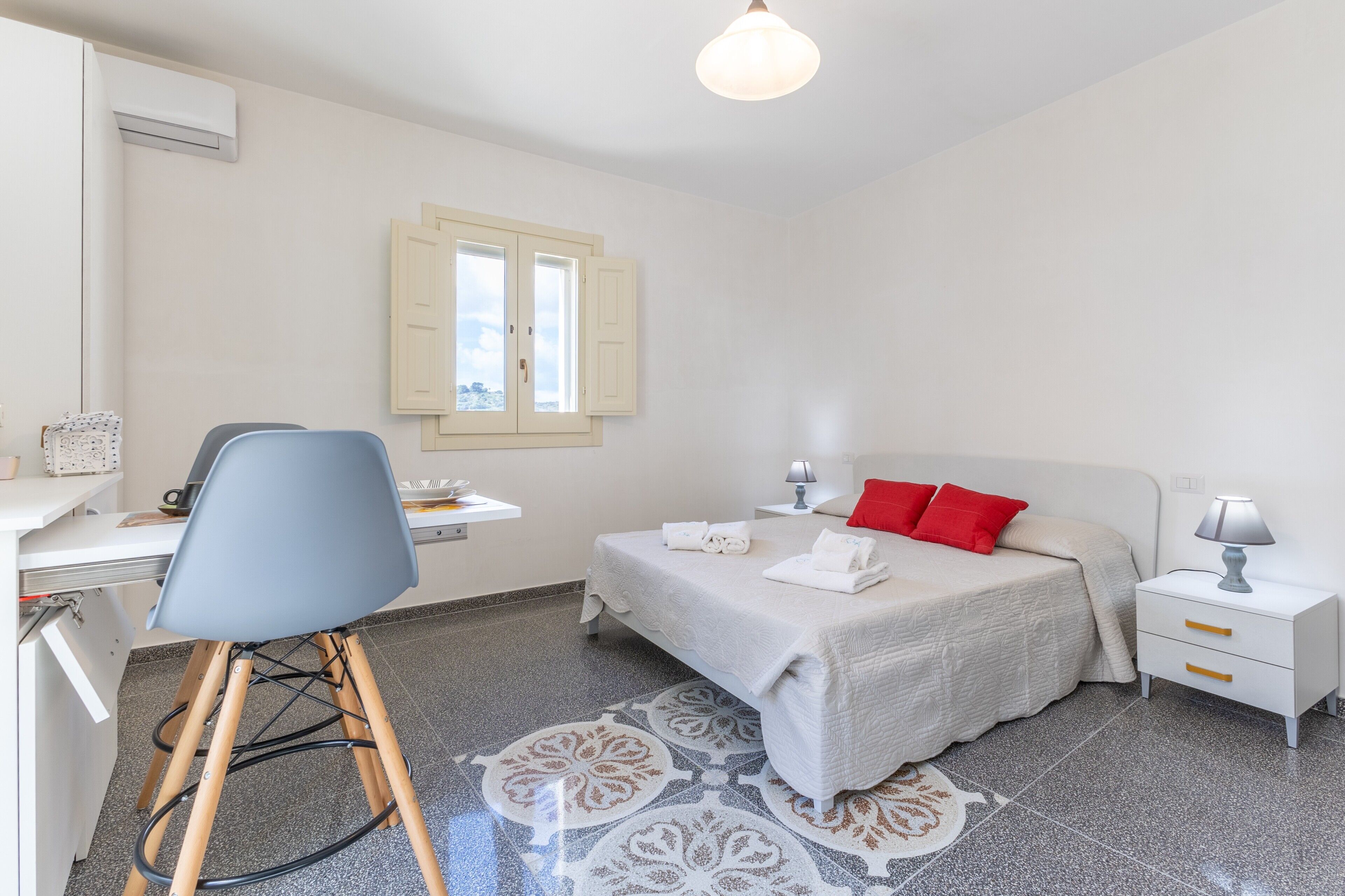 Una camera da letto con un letto, un comodino, una sedia, una scrivania e una finestra.