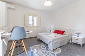 Une chambre à coucher comprenant un lit, une table de chevet, une chaise, un bureau et une fenêtre.