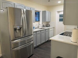 A modern kitchen with stainless steel appliances, grey cabinets, a built-in dishwasher, and a window above the sink. - City Hub: 4 Beds with Pool Table & TVs in Bedrooms, Heart of Med Center (San Antonio)