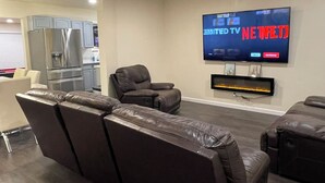 Una sala de estar moderna con un televisor de pantalla plana montado en la pared, un sofá de cuero cómodo y una chimenea empotrada.