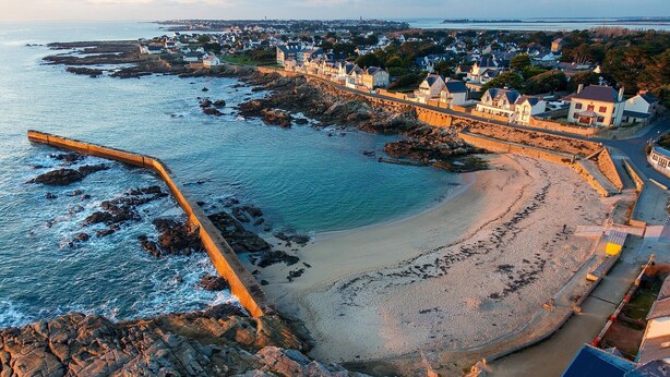 A coastal town with a beach, a pier, and residential buildings.