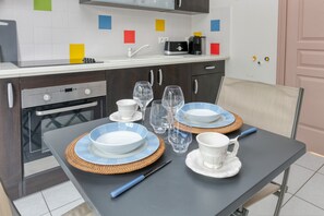 Una cocina moderna con una mesa para dos, con platos azules y blancos, vasos transparentes y un cuchillo.