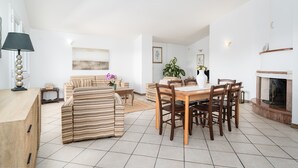 A spacious living area with a dining table, chairs, a sofa, and a fireplace.