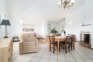 A spacious living area with a dining table, chairs, a sofa, and a fireplace.