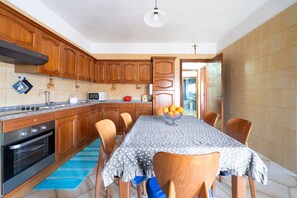 A kitchen with wooden cabinets, a stove, and a dining table with chairs.