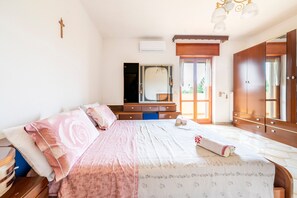 A bedroom with a bed, dresser, mirror, wardrobe, and a cross on the wall.