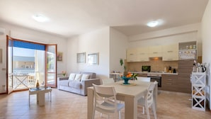 A modern apartment with a dining area, kitchen, and a balcony with a view.