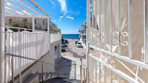 A narrow street leading to a building with a view of the sea.