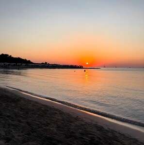 A beach with a sunset, calm water, and a row of buildings along the shore. - Room 'Li Parate' with Shared Terrace, Wi-Fi and Air Conditioning (Taviano)