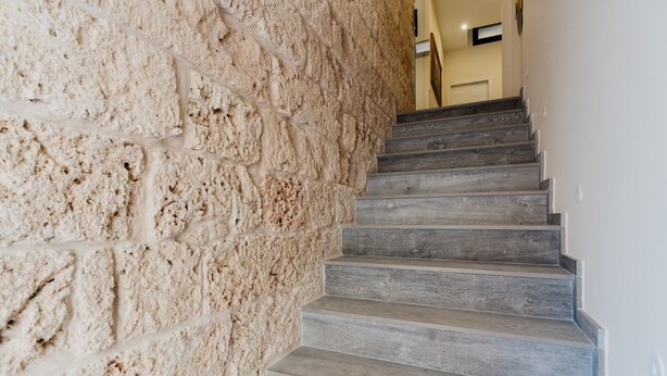 A staircase with a textured stone wall on one side and wooden steps. - Room 'Li Parate' with Shared Terrace, Wi-Fi and Air Conditioning (Taviano)
