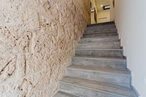 Una escalera con un muro de piedra texturizado a un lado y escalones de madera.