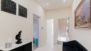 Ein modernes Interieur mit einer schwarzen Couch, einer Marmorplatte, abstrakter Wandkunst und einem Gemälde.