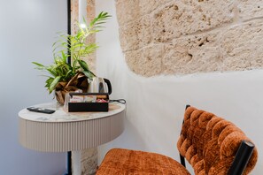A corner of a room with a round table, a potted plant, a remote control, and a chair with a textured cushion. - Apartment 'Le Capase' with Shared Terrace, Wi-Fi and Air Conditioning (Taviano)