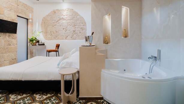 Ein modernes Badezimmer mit einer großen Badewanne, einem kleinen Tisch und einem Sessel.