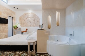 Een moderne badkamer met een groot bad, een klein tafeltje en een stoel.