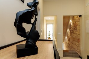 A sculpture on a wooden table in a hallway with a stone wall and a door leading to another room. - Room 'Li Pumi' with Shared Terrace, Wi-Fi and Air Conditioning (Taviano)