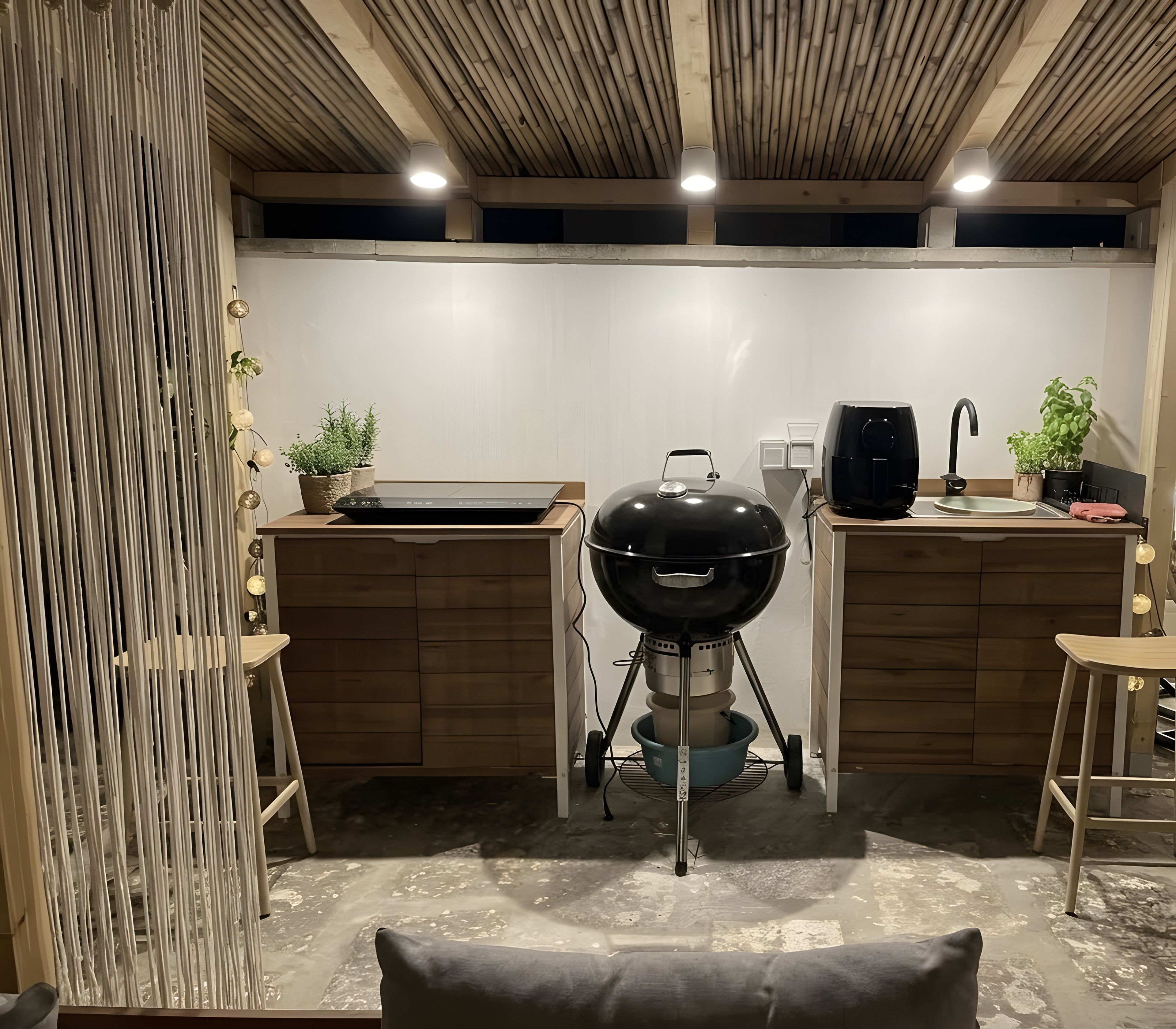Een moderne keuken met een ingebouwde grill, houten kastjes en een bamboeplafond.