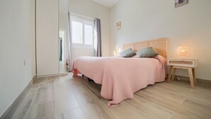 A bedroom with a bed, bedside table, lamp, and a window.
