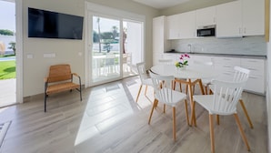 A modern kitchen with white cabinets, a flat-screen TV, and a dining area with white chairs and a table. - Villa 'Sanctipetri 10 Pax – adults over 25 only' with private pool, Wi-Fi & air conditioning (Chiclana de la Frontera)