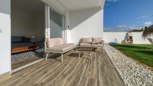 A modern outdoor patio with a sofa, a wooden table, and a glass door leading to an interior space. - Villa 'Sanctipetri 10 Pax – adults over 25 only' with private pool, Wi-Fi & air conditioning (Chiclana de la Frontera)