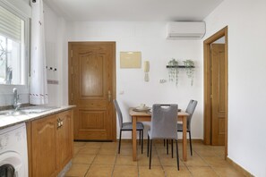 A kitchen with wooden cabinets, a washing machine, a dining table with chairs, and a door.