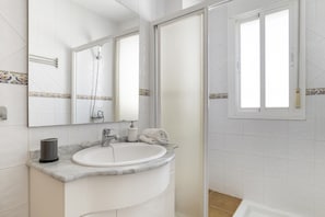 A bathroom with a white sink, mirror, and shower.
