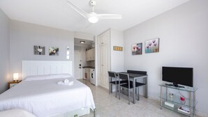 A hotel room with a bed, a desk, a television, and a ceiling fan.