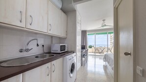 A kitchen with a washing machine, a microwave, and a sink.