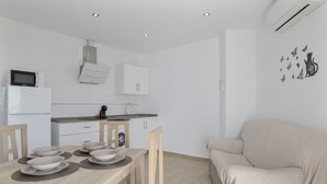 A modern kitchen with white cabinets, a microwave, and a dining table set with bowls and placemats. - Apartment 'Casa Antonia 2' with Shared Terrace, Wi-Fi and Air Conditioning (Conil de la Fra.)