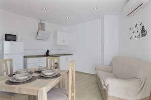 A modern kitchen with white cabinets, a microwave, and a dining table set with bowls and placemats.