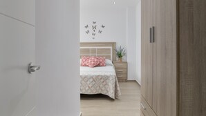A bedroom with a bed, a nightstand, a wardrobe, and a wall with butterfly decals. - Apartment 'Casa Antonia 2' with Shared Terrace, Wi-Fi and Air Conditioning (Conil de la Fra.)