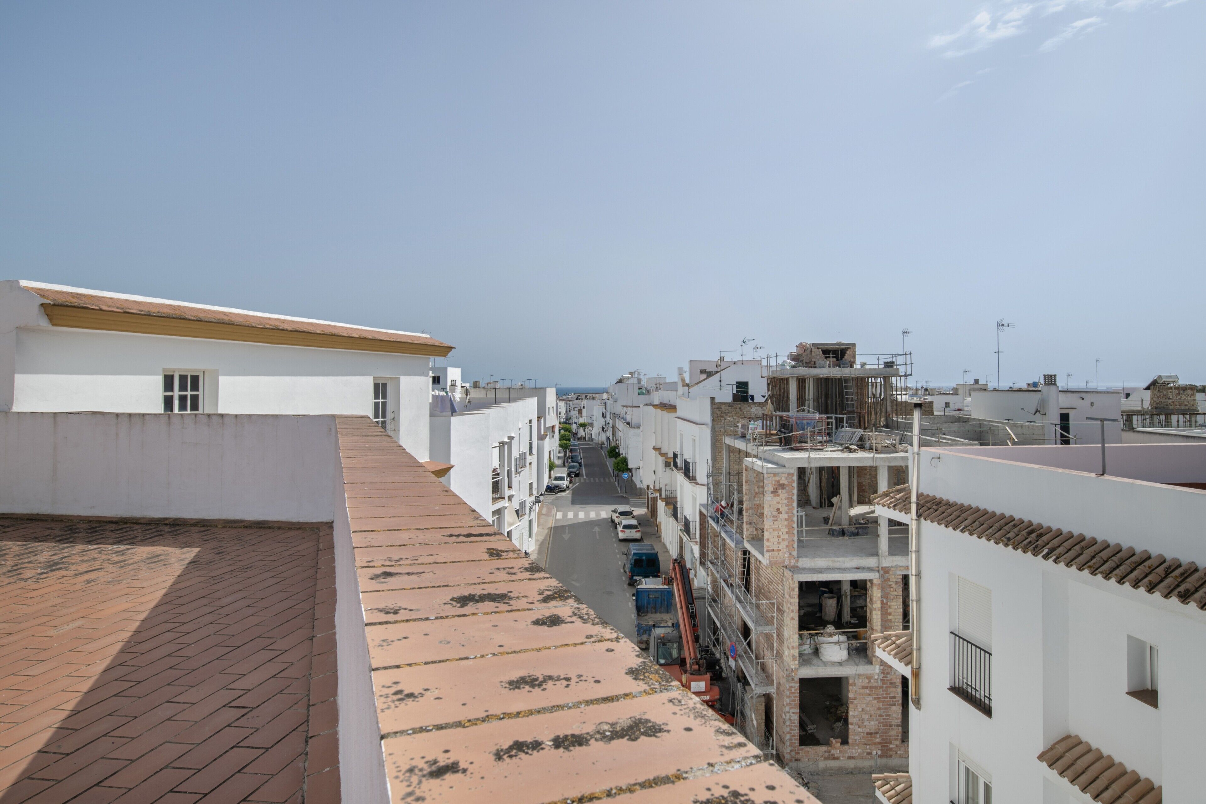 Uma rua residencial com edifícios, céu claro e calçada.