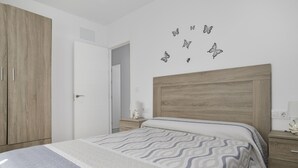 Ein Schlafzimmer mit einem Bett, einem Holzschrank, Nachttischen und Schmetterlingsstickern an der Wand.
