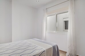 Une chambre à coucher avec un lit, une fenêtre avec des rideaux et une petite fenêtre située au-dessus du lit.