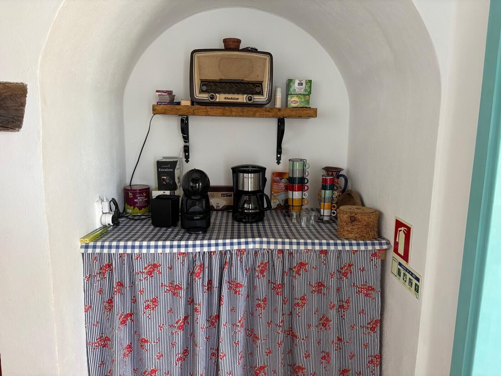 Et tekøkken med radio, kaffemaskine og diverse køkkenartikler.