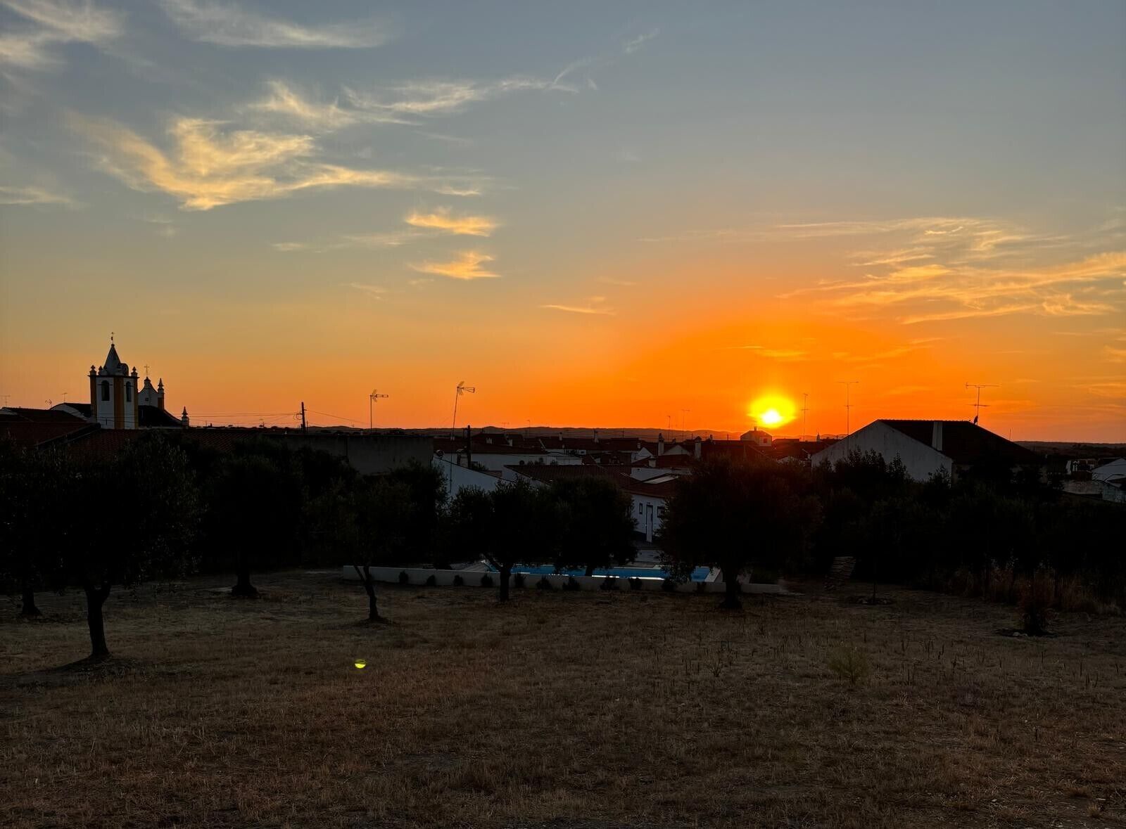 Atardecer sobre un barrio residencial con una iglesia y casas.
