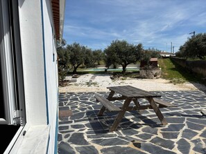 A patio with a stone floor and a wooden table.
