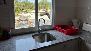 Cozinha com pia, janela e vista para um pátio externo.