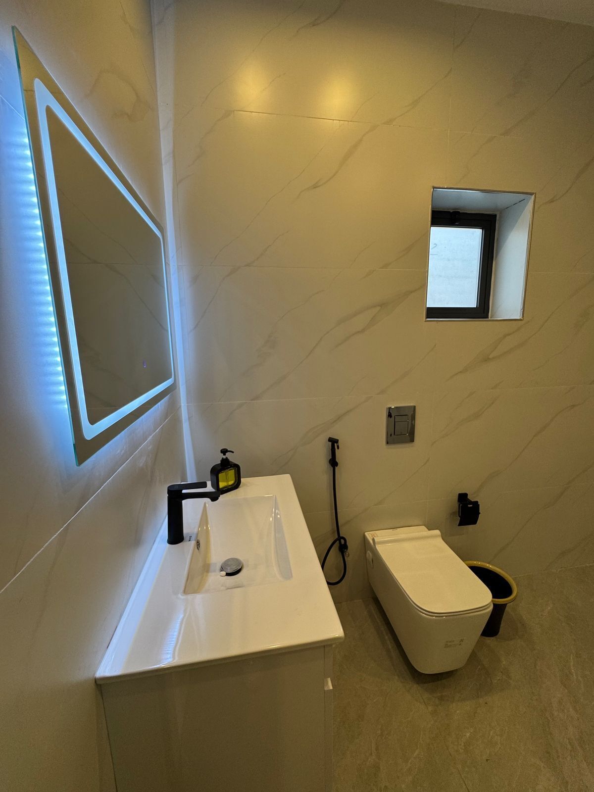 A modern bathroom with a white sink, mirror, and toilet.