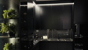 A modern kitchen with dark cabinetry, a black countertop, and a built-in plant display. - Lava villas (Ma'In)