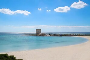 A beach with clear water, a sandy shore, and a tower structure.