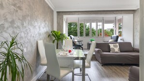 Un salon moderne avec un coin repas, de grandes fenêtres et une plante.