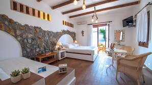 Une pièce avec un mur en pierre, un lit, une petite table avec des chaises et une vue sur l’extérieur.