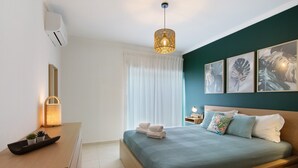 Une chambre à coucher moderne avec un lit, une table de chevet, une lampe et une œuvre d’art accrochée au mur.