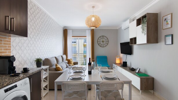Une cuisine moderne équipée d’un lave-linge, d’une table à manger pour quatre personnes et d’une chaise bleue.